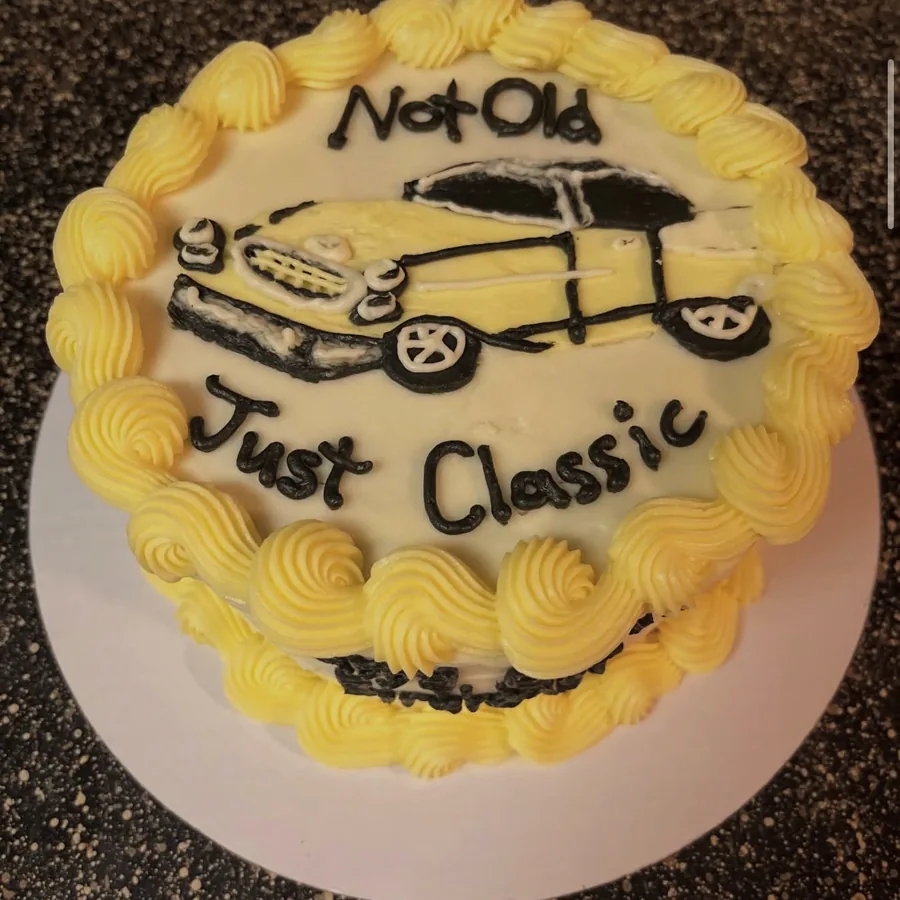 A yellow-bordered cake hand-piped with a classic car and the words Not Old Just Classic