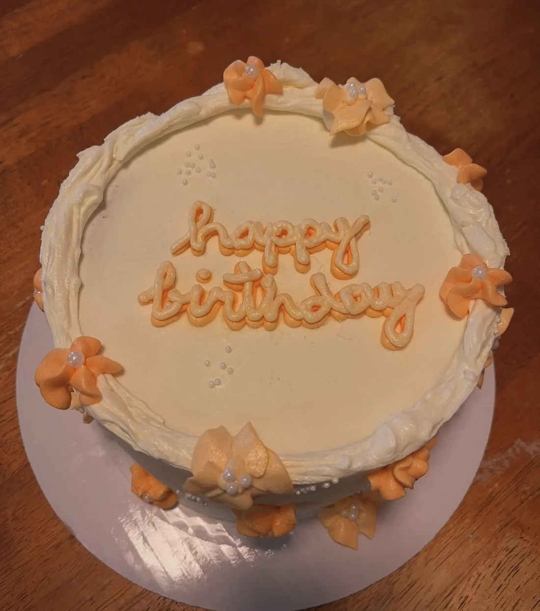A peach and cream buttercream birthday cake covered in hand-piped shell borders