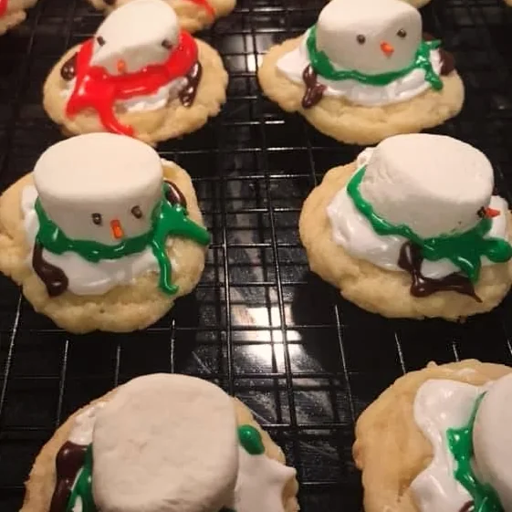 Rows of iced snowman sugar cookies cooling on a wire rack
