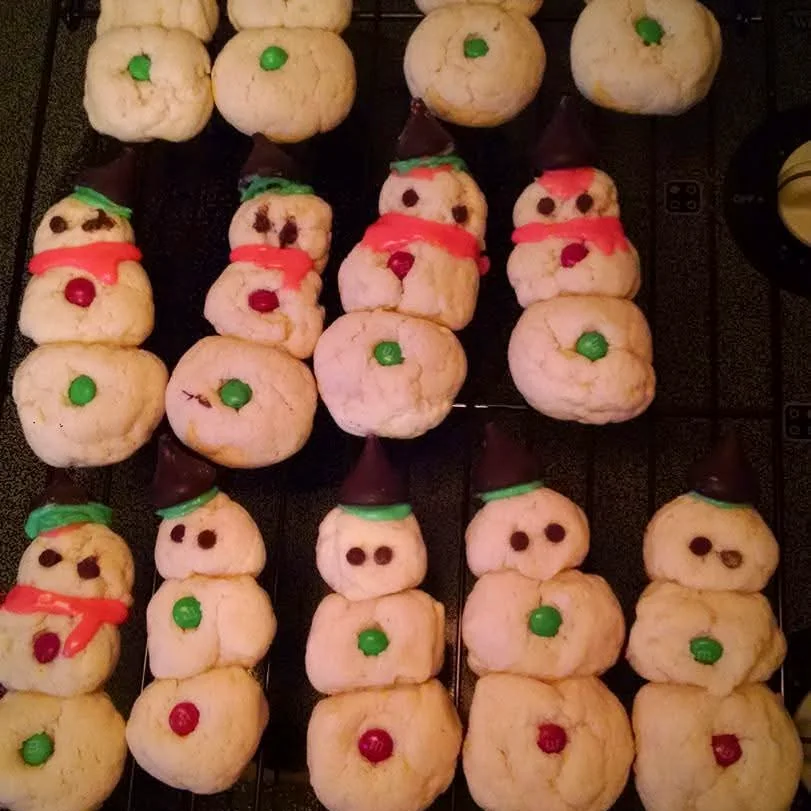 Trays of decorated snowman sugar cookies cooling on wire racks