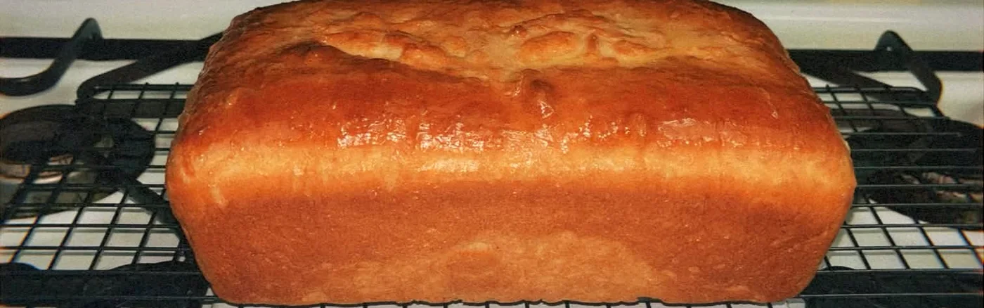 A golden loaf cooling on a wire rack set over the stove in Ava's kitchen